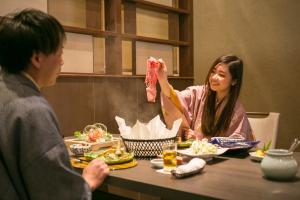 a woman holding up a piece of meat at a table at Biwako Ryokusuitei in Otsu