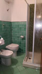 a green tiled bathroom with a toilet and a shower at Hotel Santa Croce in Florence