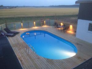 a swimming pool on a wooden deck with a table and a table at Idestrup Bed and Breakfast in Idestrup