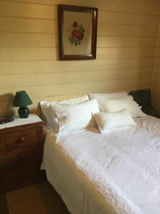 uma cama com lençóis brancos e almofadas num quarto em Twomey's Cottage em Queenscliff