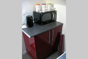 a black counter with a microwave and a tv at Studio neuf proche d'Alençon et Le mans in Lonrai