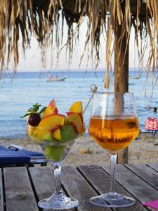 a drink and a bowl of fruit on a table on the beach at Nemo Studios in Polykhrono