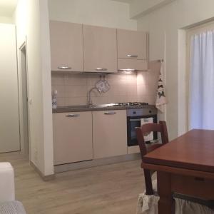 a kitchen with white cabinets and a table and a dining room at Ala Garden Apartment in Punta Ala
