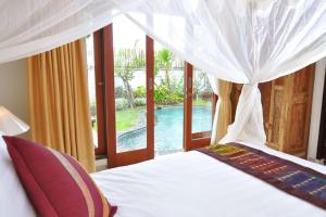 a bedroom with a bed and a view of a pool at Kandava Villa in Jimbaran