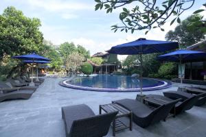 a swimming pool with blue umbrellas and chairs and a pool at Matahari Bungalow in Legian