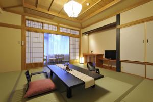 a living room with a table and chairs and a television at Hotel Seifuen in Chikuma