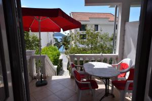 a balcony with a table and chairs and an umbrella at Nikic Apartments in Herceg-Novi