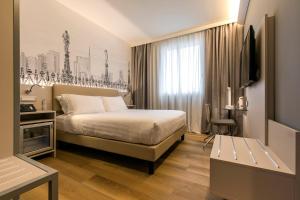 Cette chambre comprend un lit et une télévision. dans l'établissement 43 Station Hotel, à Milan