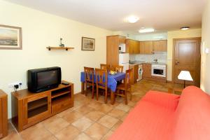 a living room with a table and a tv and a kitchen at Complejo Turístico Bielsa Hotel y camping in Bielsa