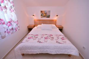 a bedroom with a bed with a pink and white comforter at Nikic Apartments in Herceg-Novi