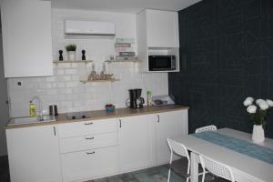 a kitchen with white cabinets and a table with a tableablish at Apartament Justyna in Stegna