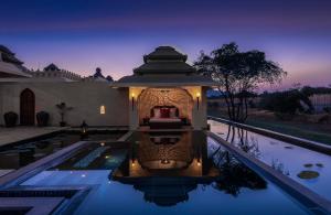 a villa with a swimming pool at night at Evolve Back Hampi in Hampi