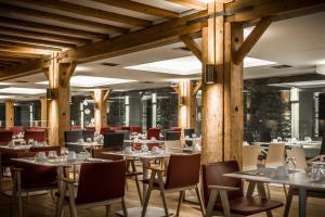 un restaurant avec des colonnes en bois, des tables et des chaises dans l'établissement Hydrama Grand Hotel, à Dráma