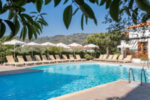 斯科派洛斯的住宿－Maistros Suites - Péra，一个带躺椅和遮阳伞的游泳池