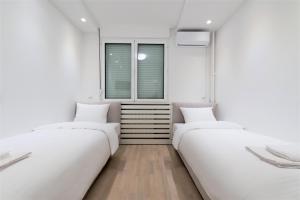 two beds in a room with two windows at Vivio Luxury Apartment in Belgrade