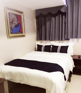 1 dormitorio con 1 cama con sábanas blancas y almohadas negras en California Hotel, en Hong Kong