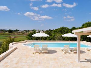 a swimming pool with two lawn chairs and umbrellas at B&B Lamie Di Olimpia in Locorotondo