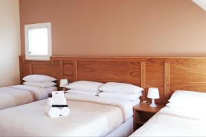 a bedroom with three beds with white sheets and a window at Bank House Guesthouse in Bundoran