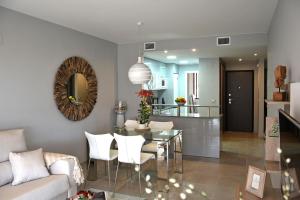 a living room with a glass table and a kitchen at Terrazas de Campoamor by Mar Holidays in Playas de Orihuela