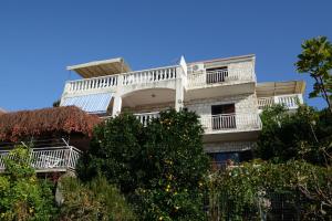 a tall white building with a balcony and trees at Apartments Marijana in Zavalatica