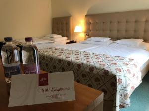 two beds in a hotel room with two bottles of wine at Hotel Hvala Superior - Topli Val in Kobarid