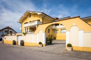 a yellow and white building with potted plants at Haus Martin - Schneeberger in Mörbisch am See