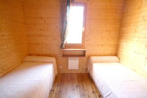 2 łóżka w małym pokoju z oknem w obiekcie Les Chalets du Domaine des Soyeux w mieście Saint-Julien-Molin-Molette