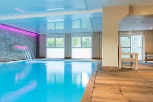 a large swimming pool in a room with a table at La Closerie SPA & Résidence Hôtel in Deauville