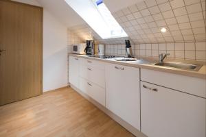 a kitchen with white cabinets and a sink and a window at Ferienhaus Thönnes in Norderney