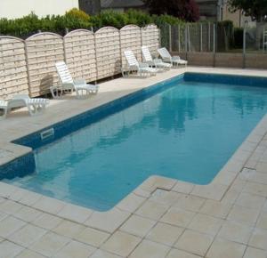 uma piscina com cadeiras e um grupo em Residence des Bains em Carantec