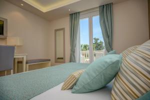 パデンゲ・スル・ガルダにあるHotel Villa Garutiのベッドルーム1室(青い枕のベッド1台、窓付)