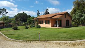 une petite maison avec une pelouse verte en face de celle-ci dans l'établissement Agriturismo Rebua, à Porto Azzurro