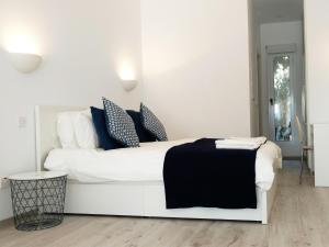a white bed with blue pillows in a white room at Olosuites in Limassol