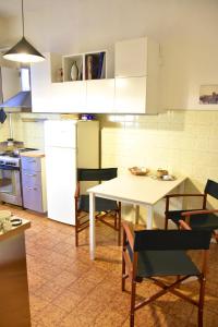 una cocina con mesa y sillas y una cocina con armarios blancos. en A casa del cuoco, en Florencia