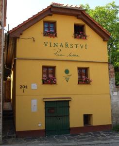 un edificio amarillo con una puerta verde y ventanas en Vinarstvi Radim Mildner, en Podivín