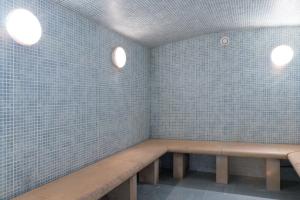 a row of benches in a room with blue tiles at La Closerie SPA & Résidence Hôtel in Deauville