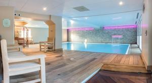 a pool in a room with a table and chairs at La Closerie SPA & Résidence Hôtel in Deauville