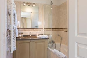 a bathroom with a sink and a shower and a mirror at La Closerie SPA & Résidence Hôtel in Deauville