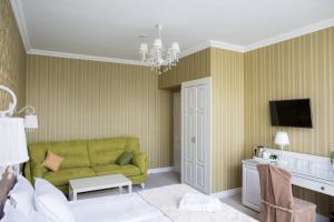 a living room with a green couch and a tv at Boutique Hotel Deluxe in Kamianets-Podilskyi