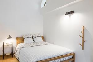 een witte slaapkamer met een bed en een lamp bij Odorico by Cocoonr in Rennes