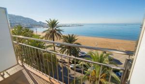 uma varanda com vista para uma praia e palmeiras em Hotel Risech em Roses