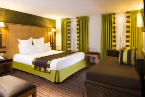パリにあるホテル　モンディアルの大きなベッドとソファが備わるホテルルームです。