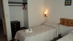 Dormitorio pequeño con 2 camas y una luz en la pared en Entre Sierras en Villa General Belgrano