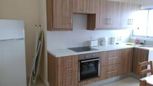 Una cocina con gabinetes de madera, un fregadero y un refrigerador. en Modern City Center Apt, en Lárnaca
