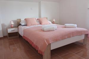 a bedroom with a large bed with pink pillows at Maria's Paradise in Nin