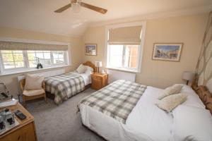 a bedroom with two beds and a chair and windows at The Maples in Hythe