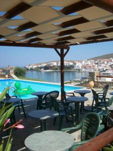a patio with tables and chairs and a swimming pool at Vassiliki Studios in Andros