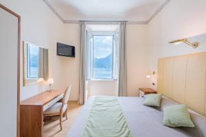 a bedroom with a bed and a desk and a window at Villa Belvedere Como Lake Relais in Argegno