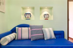 un divano blu con tre cuscini e ritratti sul muro di Estate4home - Henry House a Sorrento