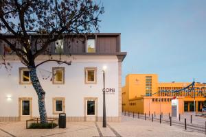 um edifício com uma árvore em frente em Hostel Conii & Suites Algarve em Quarteira